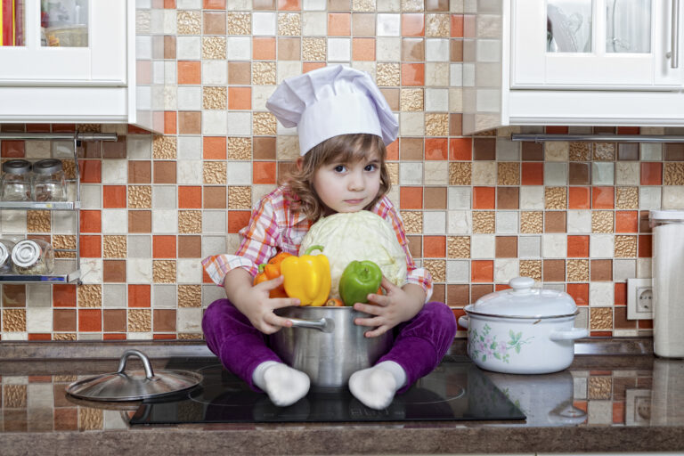 girl cook with fresh vegetables sits on a kitchen table