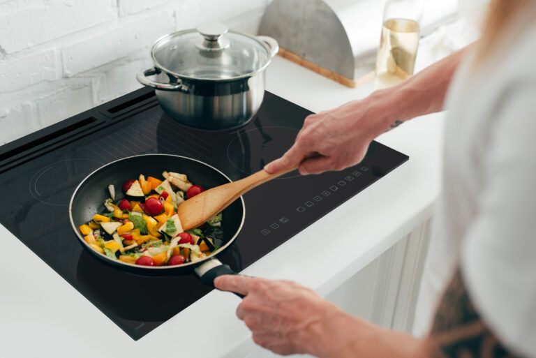 cropped shot of man cooking vegetables in frying pan on electric